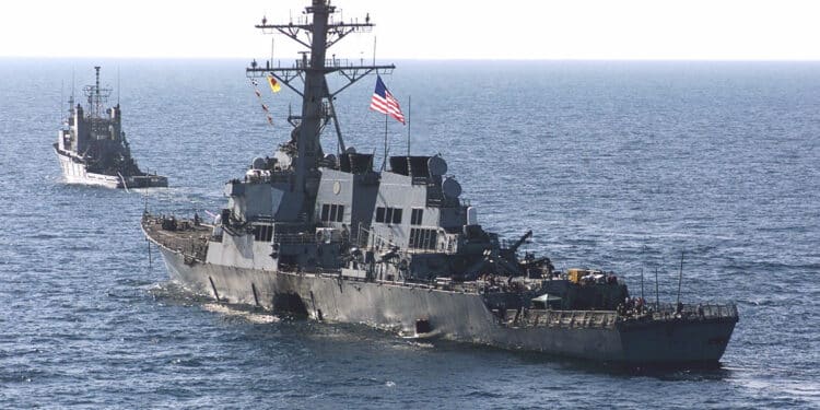 Before 9/11: The Day Terror Struck the USS Cole and Changed the U.S. Military 1 001029-M-0557M-011
The USS Cole (DDG 67) is towed away from the port city of Aden, Yemen, into open sea by the Military Sealift Command ocean-going tug USNS Catawba (T-ATF 168) on Oct. 29, 2000. Cole will be placed aboard the Norwegian heavy transport ship M/V Blue Marlin and transported back to the United States for repair. The Arleigh Burke class destroyer was the target of a suspected terrorist attack in the port of Aden on Oct. 12, 2000, during a scheduled refueling. The attack killed 17 crew members and injured 39 others. DoD photo by Sgt. Don L. Maes, U.S. Marine Corps. (Released)